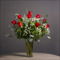 Red roses arranged in a clear glass vase with white filler flowers