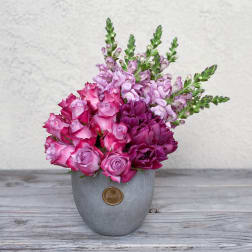 Pink and purple flowers arranged in a gray vase