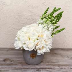 White floral arrangement in a gray vase with green spikes