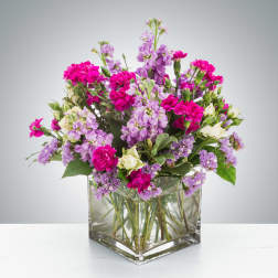 Bright pink and lavender mixed flower arrangement in a clear glass cube vase