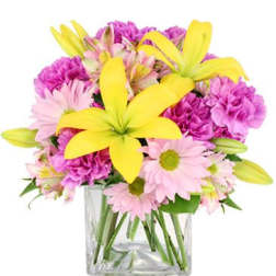 Pink and yellow mixed flowers arranged in a clear glass vase