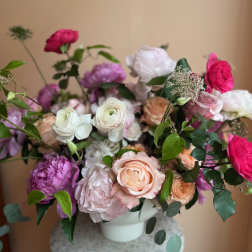 Mixed bouquet of pink, white, and peach flowers in a white vase