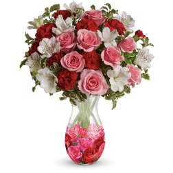 Pink roses, red carnations, and white alstroemeria arranged in a printed glass vase