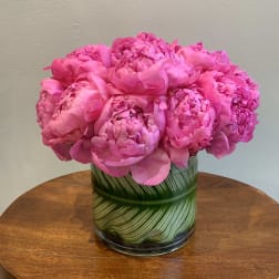 Pink peonies arranged in a glass vase with green leaf pattern