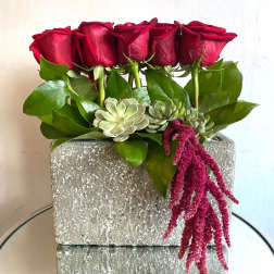Red roses and succulents arranged in a gray rectangular planter