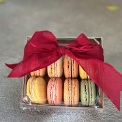 Box of colorful macarons tied with a red ribbon