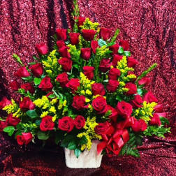 Large bouquet of red roses with yellow filler flowers in a white basket
