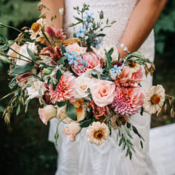 Bridal bouquet of blush, peach, and blue flowers
