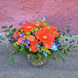 Bright mixed bouquet in a glass vase with orange and blue flowers