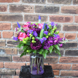 Pink and purple flower arrangement in a glass jar vase