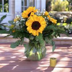 Sunflower bouquet in a glass vase with a small candle nearby