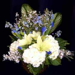 White hydrangeas and pale yellow lilies in a basket with blue accents