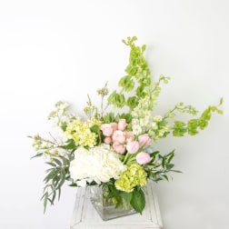 Bouquet of white and pink flowers in a clear square vase