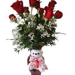 Red roses in a vase with a teddy bear bow