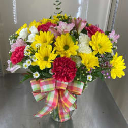 Mixed bouquet of yellow daisies, pink carnations, and white roses in a glass vase