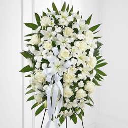 White funeral spray with roses and lilies on a stand