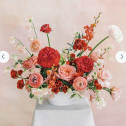 Pink and red floral arrangement in a white bowl vase