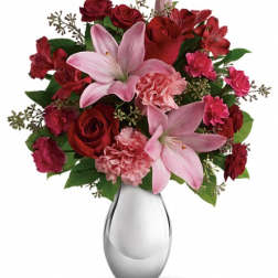 Pink lilies and red roses arranged in a clear glass vase