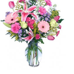 Mixed bouquet of pink lilies, tulips, carnations, and daisies in a clear glass vase
