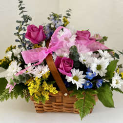 Basket arrangement with pink roses, white daisies, and a pink ribbon