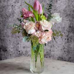 Pink tulips and pale roses arranged in a clear glass vase