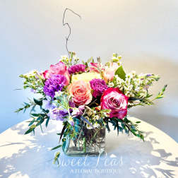 Mixed pink and purple bouquet in a square glass vase
