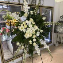 Large white funeral spray on a stand with cascading flowers