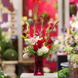 Red roses and white lilies in a red glass vase