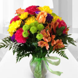 Colorful mixed bouquet in a glass vase with a green ribbon