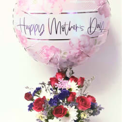 Mother's Day balloon above a red, white, and purple flower arrangement in a white pot