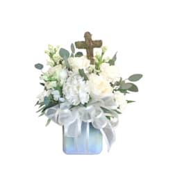 White floral arrangement with a moss cross in a square vase and sheer white bow