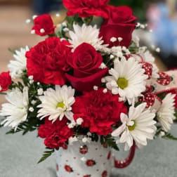 Red roses and white daisies in a patterned mug
