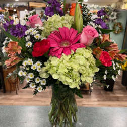 Mixed bouquet in a glass vase with pink, purple, green, and white flowers