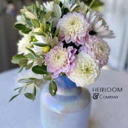 Pink and white flowers arranged in a glass vase with greenery