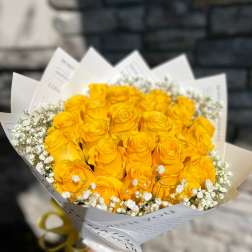 Bouquet of yellow roses with white baby's breath in white paper wrap