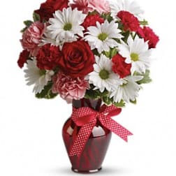 Red and white mixed bouquet in a red vase with a ribbon