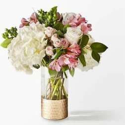 Pink and white bouquet in a clear glass vase with a gold wrap