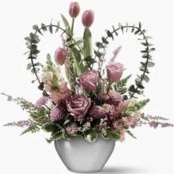 Pink tulips and roses arranged in a gray vase with heart-shaped greenery