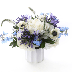White and purple floral arrangement in a white vase with blue accents