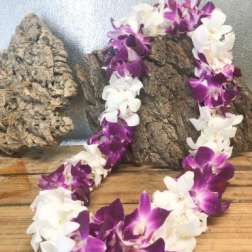 Purple and white orchid lei draped over wood