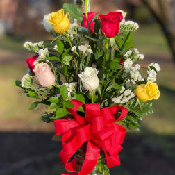Mixed roses in a glass vase with a red ribbon bow