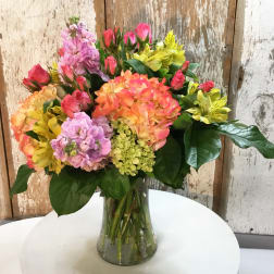 Mixed bouquet of pink, orange, and yellow flowers in a glass vase