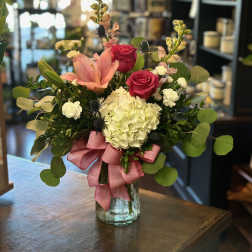 Pink roses and lilies in a glass vase with a pink ribbon