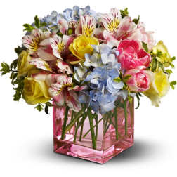 Bouquet of mixed flowers in a pink glass cube vase