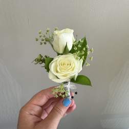Small white rose boutonniere with greenery and ribbon