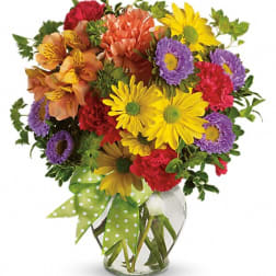 Colorful mixed bouquet in a clear glass vase with a polka-dot ribbon
