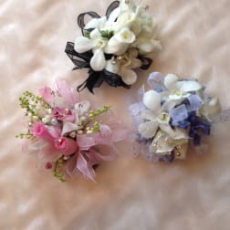 Three small floral corsages with white, pink, and lavender flowers
