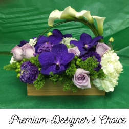 Purple and white floral arrangement in a wooden basket with arched calla lilies