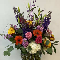 Colorful mixed bouquet in a glass vase with tall purple accents