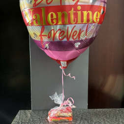 Heart-shaped Valentine balloon with a candy gift bundle below